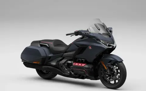 Ciemnoszary motocykl Honda Gold Wing z czarnym siedzeniem i kuframi, gotowy na dalekie podróże.