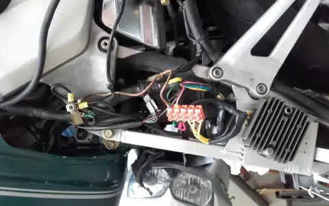 Widok instalacji elektrycznej skutera z widocznymi bezpiecznikami i przewodami.