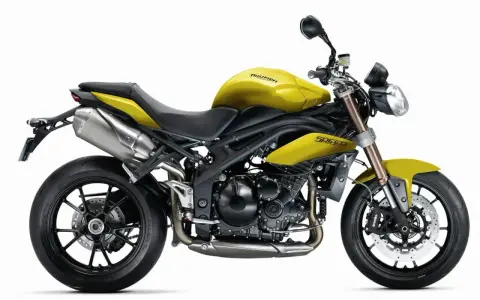 Żółty motocykl Triumph Speed Triple 1050 z czarnymi felgami i wydechem.