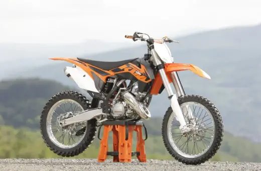 Pomarańczowy KTM SX 125 gotowy do osiągnięcia v-max na górskich trasach.