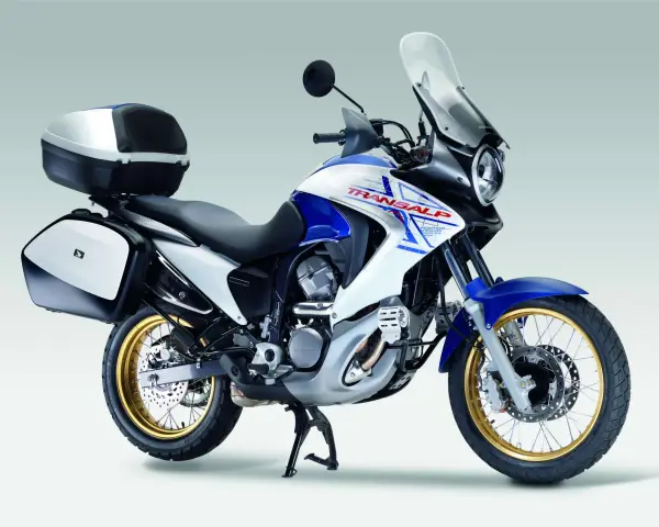 Honda Transalp 700 dane techniczne: turystyczny motocykl z kuframi, biało-niebieski, złote felgi, gotowy na przygodę.
