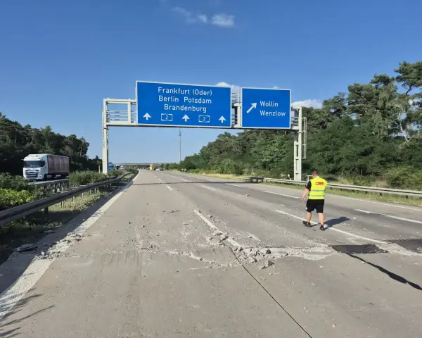 Uszkodzona autostrada A2 Niemcy. Na drodze leżą gruzy, a pracownik w kamizelce odblaskowej ogląda zniszczenia.