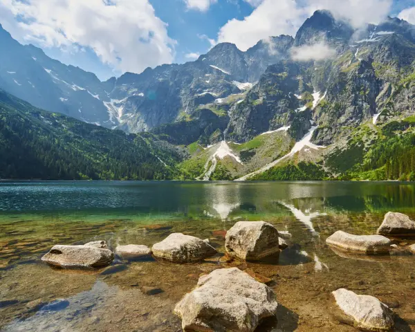 Kamienista droga na Morskie Oko prowadzi przez malownicze Tatry. Jezioro odbija skaliste szczyty i zielone lasy.