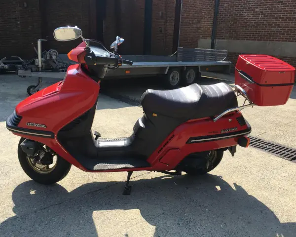 Czerwony skuter Honda Spacy 250 z kufrem, gotowy do podróży.