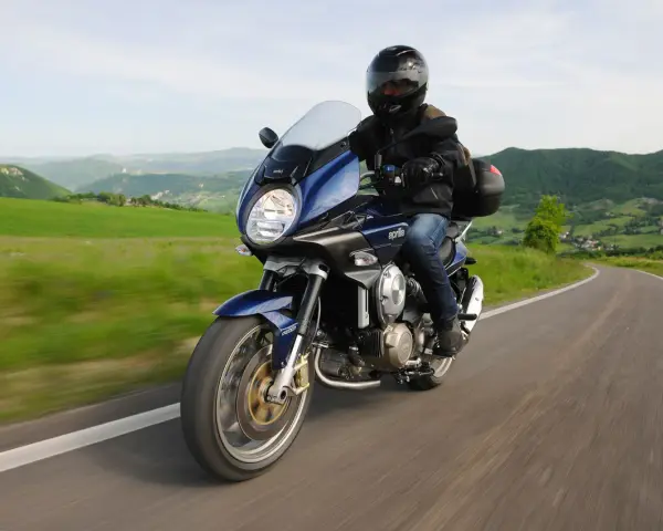 Motocykle szosowo turystyczne przemierzają malownicze, zielone wzgórza.