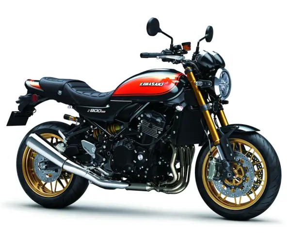 Stylowy czarny motocykl Kawasaki Z900RS z pomarańczowo-żółtym malowaniem na baku i złotymi felgami.