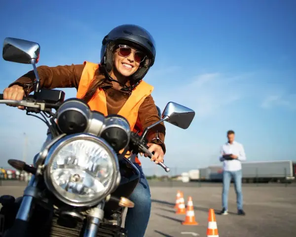 Uśmiechnięta kursantka na motorze, gotowa na egzamin. Zastanawiasz się, jakie prawo jazdy na motor 1000? To kategoria A.