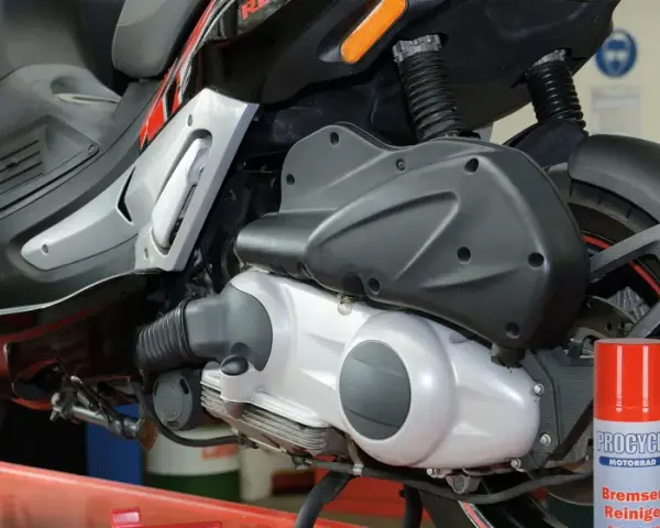 Skuter Gilera z widocznym silnikiem 4t. Może to być przyczyna, dla której po dodaniu gazu silnik się dusi. Obok stoi spray do czyszczenia hamulców.