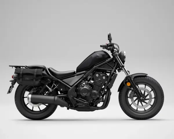 Czarny motocykl Honda Rebel 500 z sakwami, gotowy na podróż. Jego prędkość maksymalna pozwala na swobodne pokonywanie tras.