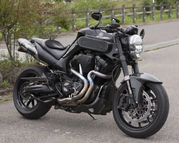 Czarny Yamaha MT-01 z customowym wydechem i sportowymi dodatkami, gotowy na jazdę po krętych drogach.