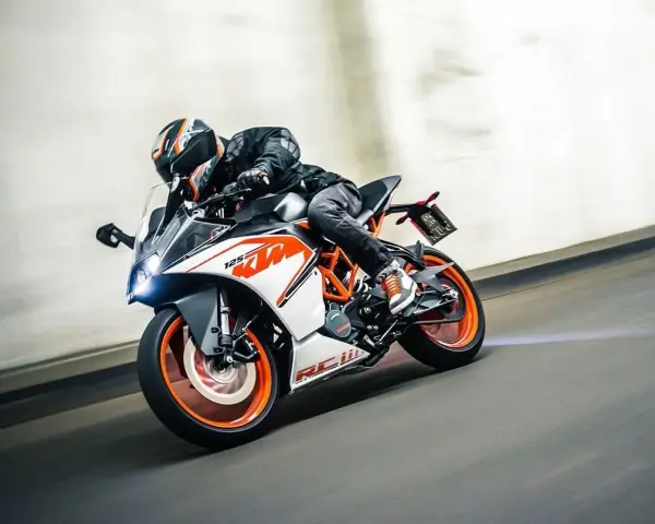 Motocyklista w kasku śmiga na KTM RC 125, osiągając maksymalną prędkość na torze.