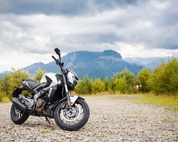 Biało-czarny Bajaj Dominar 400 na tle gór i chmur. Gotowy na przygodę w dziczy.