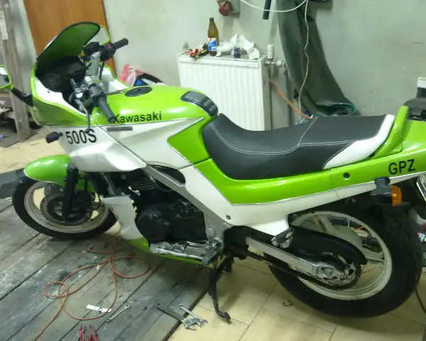 Zielono-biały motocykl Kawasaki GPZ 500 z napisem "GPZ" na tyle. Stoi na drewnianej podłodze w garażu.