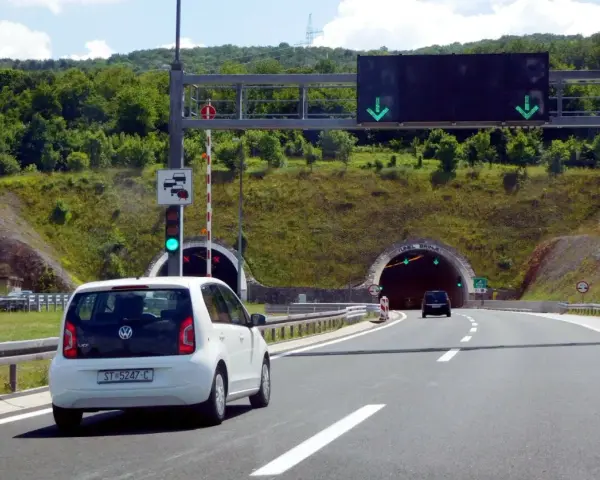 W Chorwacji są płatne autostrady. Biały samochód zbliża się do tunelu, sygnalizacja świetlna zielona.