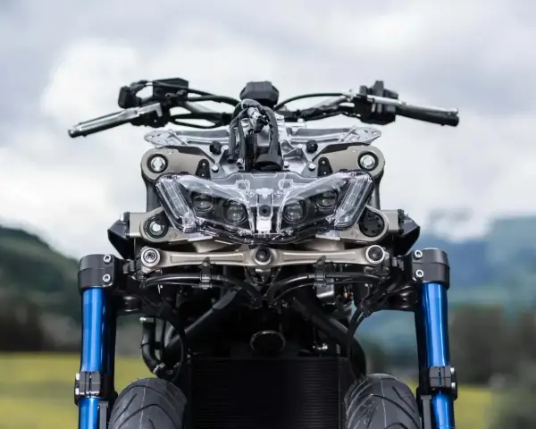 Przód motocykla Yamaha Niken GT z niebieskimi lagami i charakterystycznym, wielopunktowym reflektorem.