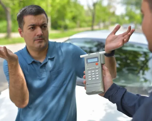 Mężczyzna z niedowierzaniem pyta, ile można mieć promili w Polsce, gdy policjant pokazuje mu alkomat.