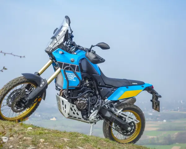 Niebiesko-żółty motocykl Yamaha Tenere 700 Rally gotowy na przygodę na wzgórzu.