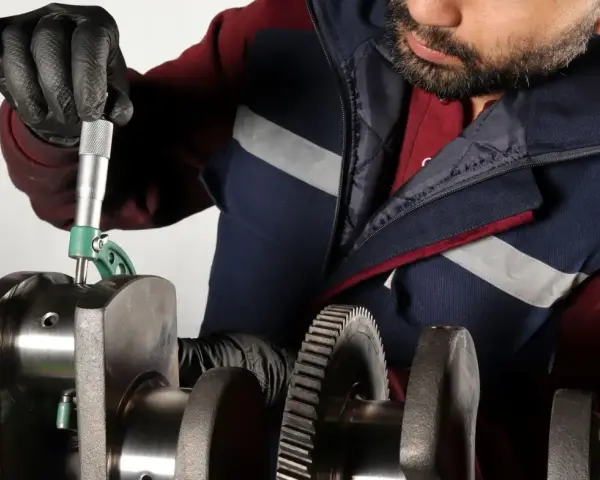 Mechanik mierzy wał korbowy, sprawdzając, czy nie ma uszkodzonej panewki.