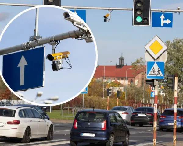 Zbliżenie na kamery monitoringu przy drogowskazie z białym strzałką w górę.