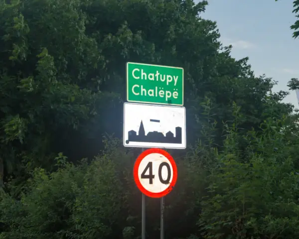 Znak d42: Chatupe Chalëpe, zarys zabudowań i ograniczenie prędkości do 40 km/h.