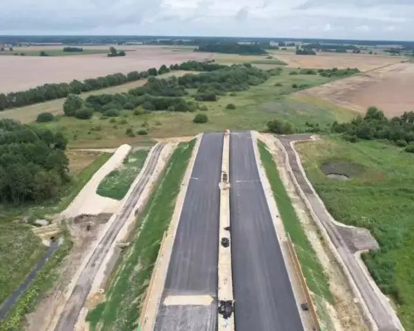Budowa drogi ekspresowej S2 Siedlce-Biała Podlaska. Nowa nawierzchnia asfaltowa w otoczeniu zieleni i pól.