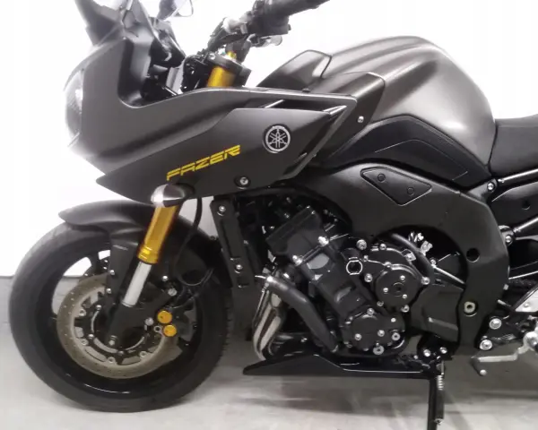 Ciemnoszary motocykl Yamaha FZ8 z żółtym napisem "FAZER" na baku. Widoczny fragment przedniego koła, zawieszenia i silnika.