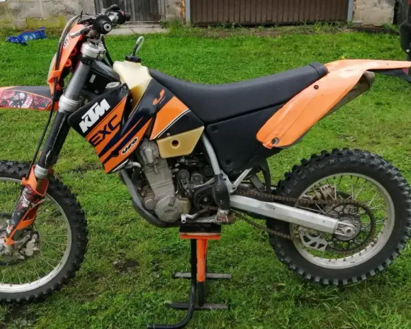 Pomarańczowy motocykl KTM 400 EXC na stojaku, gotowy do jazdy po bezdrożach.