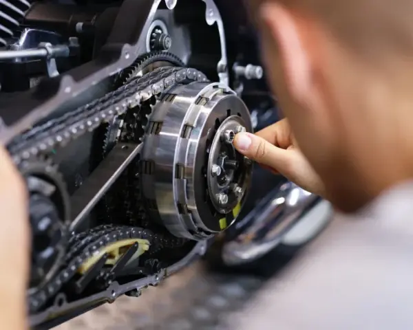 Mechanik reguluje sprzęgło, kluczowy element do nauki, jak zmieniać biegi w motocyklu 125.