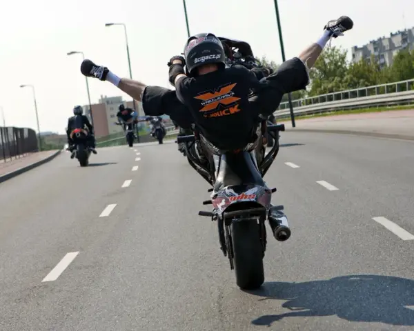 Motocyklista wykonuje jazdę na jednym kole, rozkrokiem. Ryzykowne wyczyny mogą skończyć się mandatem.