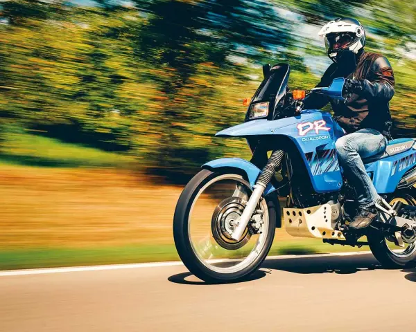 Motocyklista na niebieskim Suzuki DR 800 Big pędzi po drodze. Poznaj suzuki dr 800 big dane techniczne i poczuj wolność.