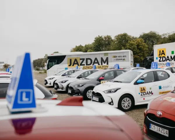 Auta szkoleniowe z literą "L" na dachu, gotowe do nauki różnych kategorii prawa jazdy.