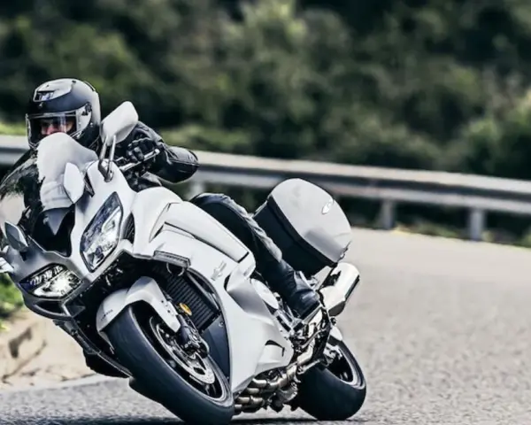 Motocyklista w kasku pochyla się na białym motocyklu Yamaha FJR 1300, pokonując zakręt. Dane techniczne tego modelu są imponujące.