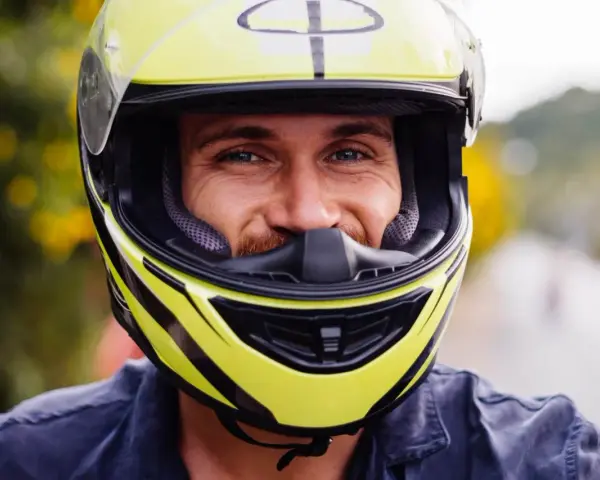Uśmiechnięty mężczyzna w żółtym kasku motocyklowym.