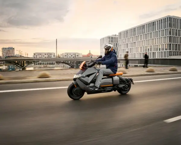 Mężczyzna w kasku jedzie na skuterze BMW CE 04 po mieście.