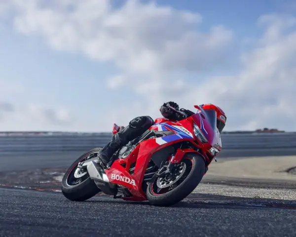 Czerwony motocykl Honda CBR650R z kierowcą pochylonym na zakręcie toru wyścigowego.