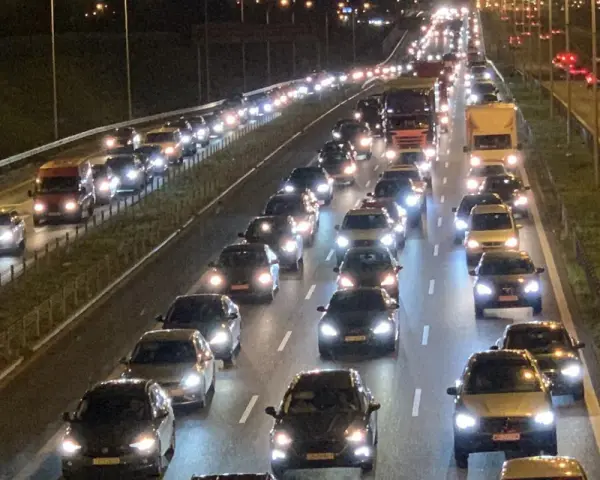 Nocny korek na drodze S8. Długi sznur samochodów i ciężarówek z zapalonymi światłami tworzy świetlisty tunel.