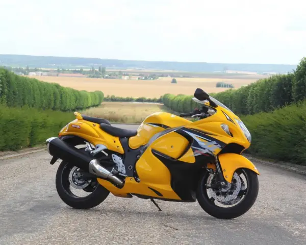 Żółty Suzuki Hayabusa na tle pól i zielonych żywopłotów. Sprawdź aktualną suzuki hayabusa cena!