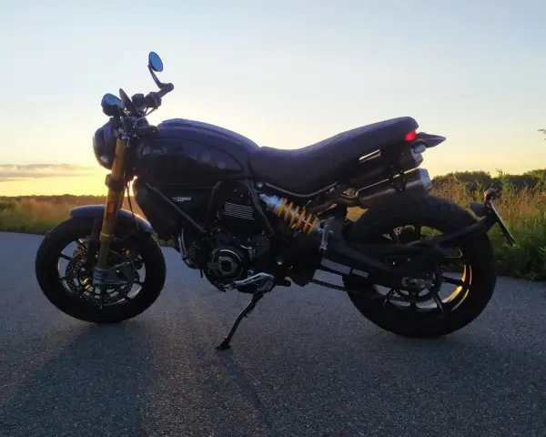 Czarny Ducati Scrambler 1100 na tle zachodzącego słońca. Idealny na wieczorną przejażdżkę.