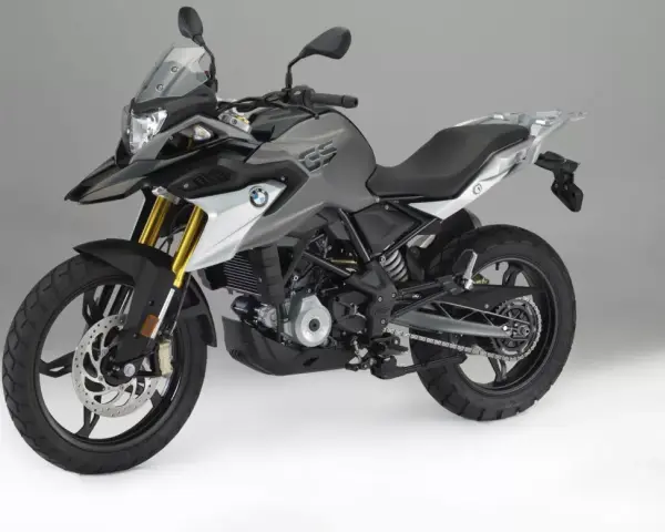 Szary motocykl BMW 310 GS z czarnym siedzeniem i złotymi amortyzatorami, gotowy na przygodę.