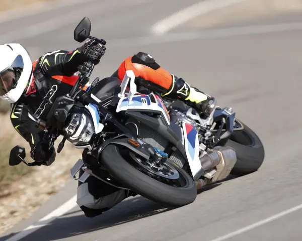 Motocyklista w kombinezonie i kasku pochyla się na zakręcie na sportowym motocyklu BMW. DTC BMW zapewnia kontrolę.