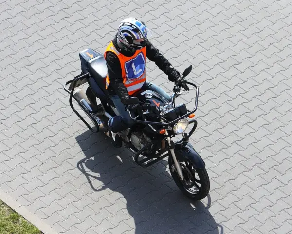 Motocyklista w kamizelce z literą "L" (kategoria A2) na placu manewrowym.