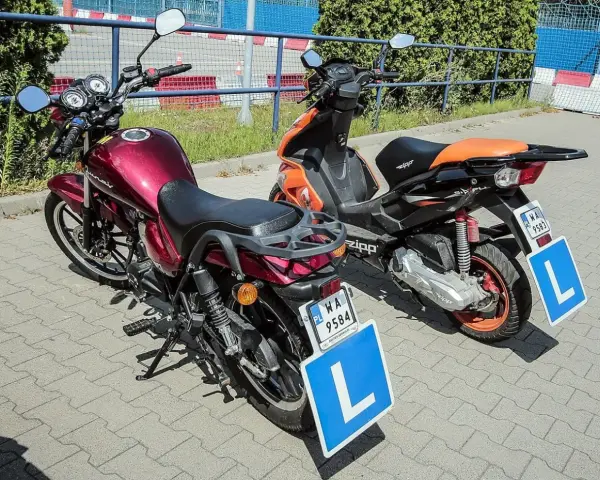 Dwa pojazdy, motorower i skuter, gotowe do nauki jazdy. Na każdym z nich widnieje tablica z literą "L", symbolizująca kartę motorowerową.
