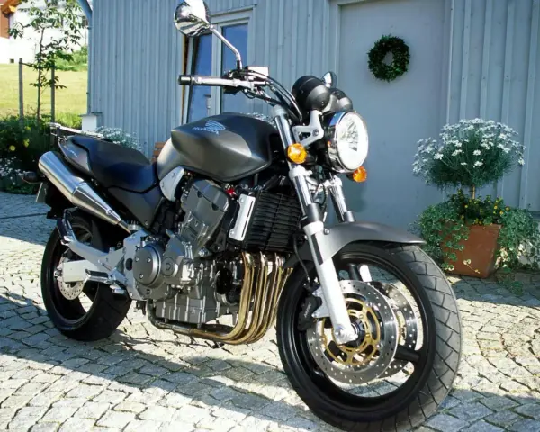 Szary motocykl Honda 919 zaparkowany na bruku przed domem.