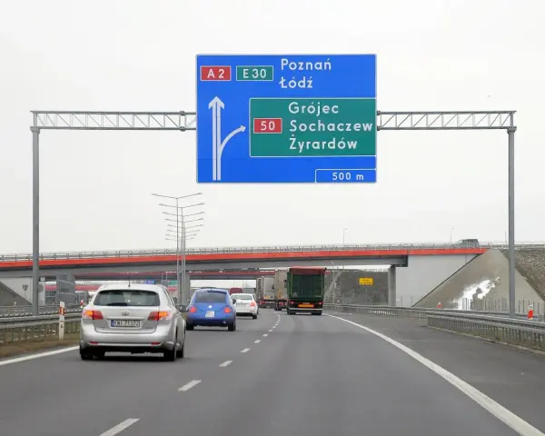 Autostradą A2 w kierunku Poznania i Łodzi. Znak informuje o minimalnej prędkości na autostradzie i zjeździe na Grójec, Sochaczew, Żyrardów za 500 m.