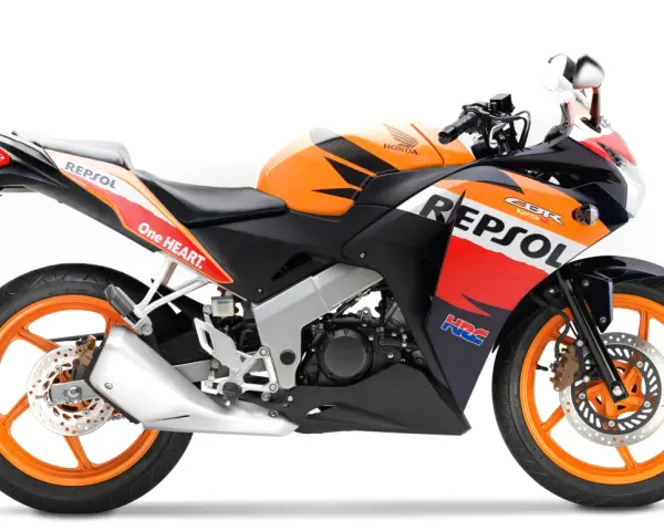 Pomarańczowo-czarny motocykl Honda CBR 125R w barwach Repsol, gotowy do wyścigów.