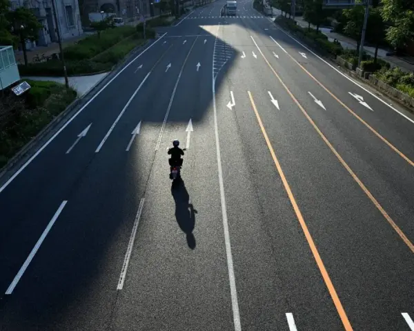 Samotny motocyklista na pustej drodze, cień rzuca się na asfalt. Zastanawia się, jak wyrejestrować skuter.