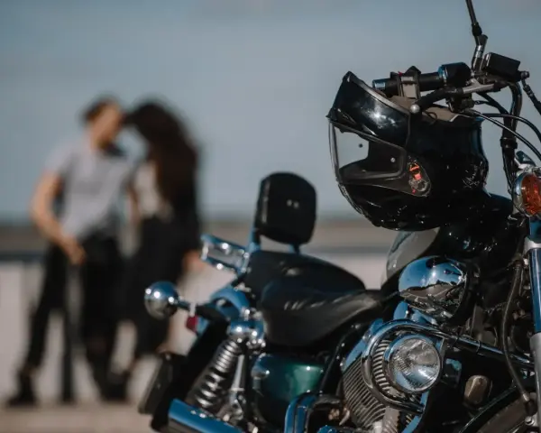 Motocykl z kaskiem na kierownicy, w tle para w czułym uścisku. Idealny dzień na wspólną podróż 4t.