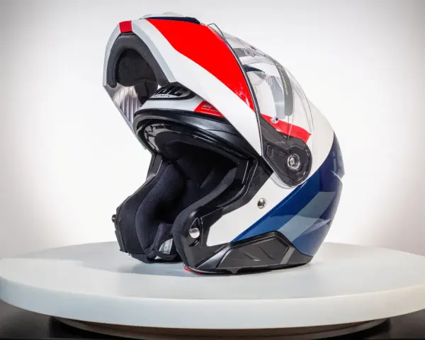 Kask motocyklowy z podniesioną szczęką, w kolorach białym, czerwonym i niebieskim, na białym tle.