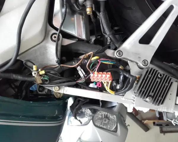 Widok instalacji elektrycznej skutera z widocznymi bezpiecznikami i przewodami.