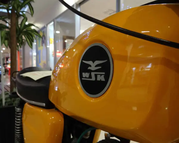 Żółty bak motocykla WSK 125 z charakterystycznym logo. Ile koni kryje się pod tą błyszczącą karoserią?